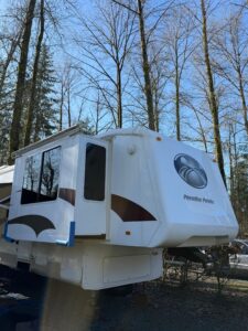 White RV parked among tall trees